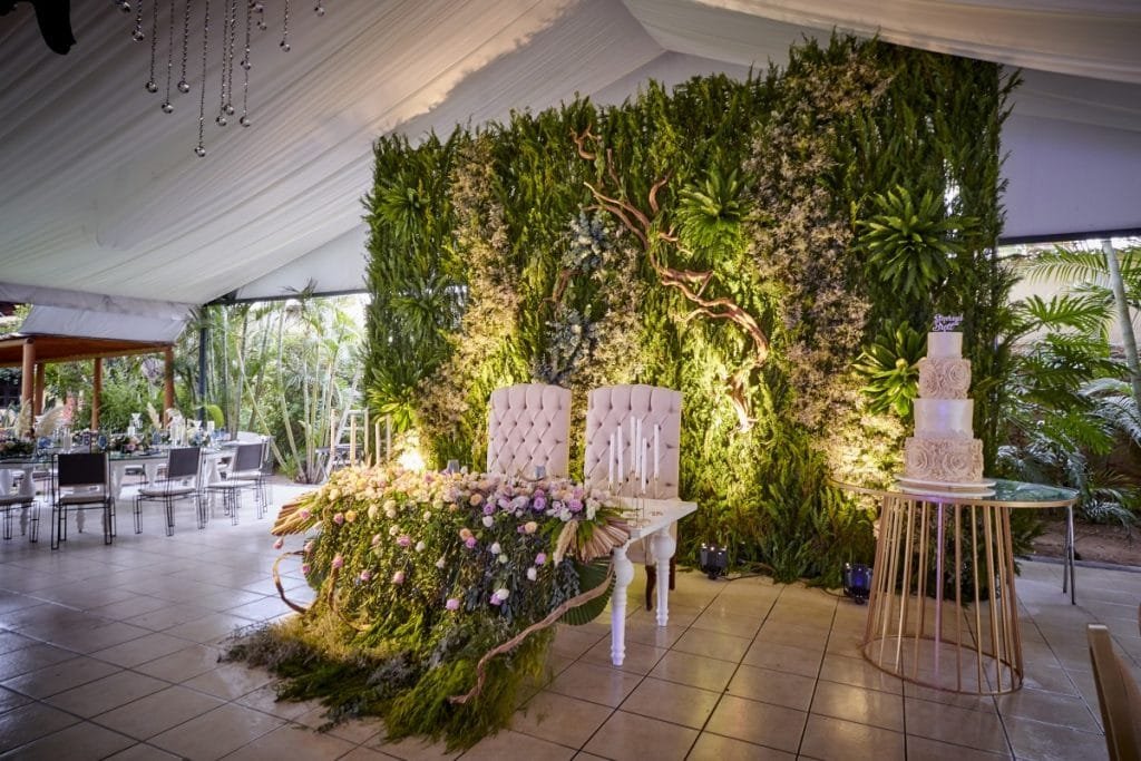 Floral green wall backstage main wedding table with white cake, shite ceilings